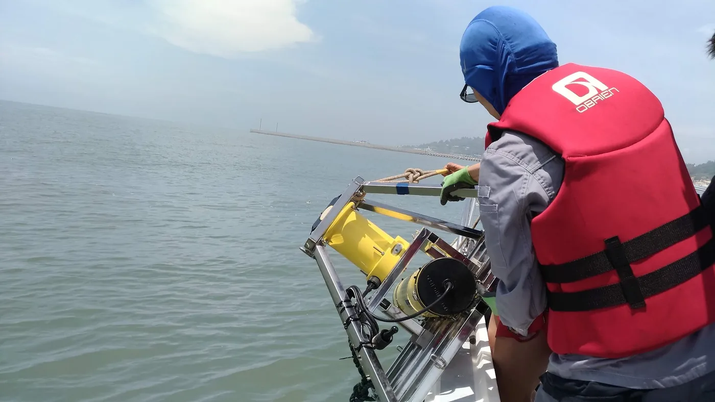 Researcher in a life jacket handling a moored instrument at sea